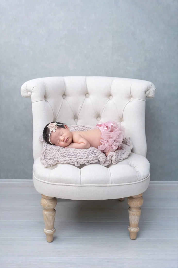 白い椅子の上で眠る新生児