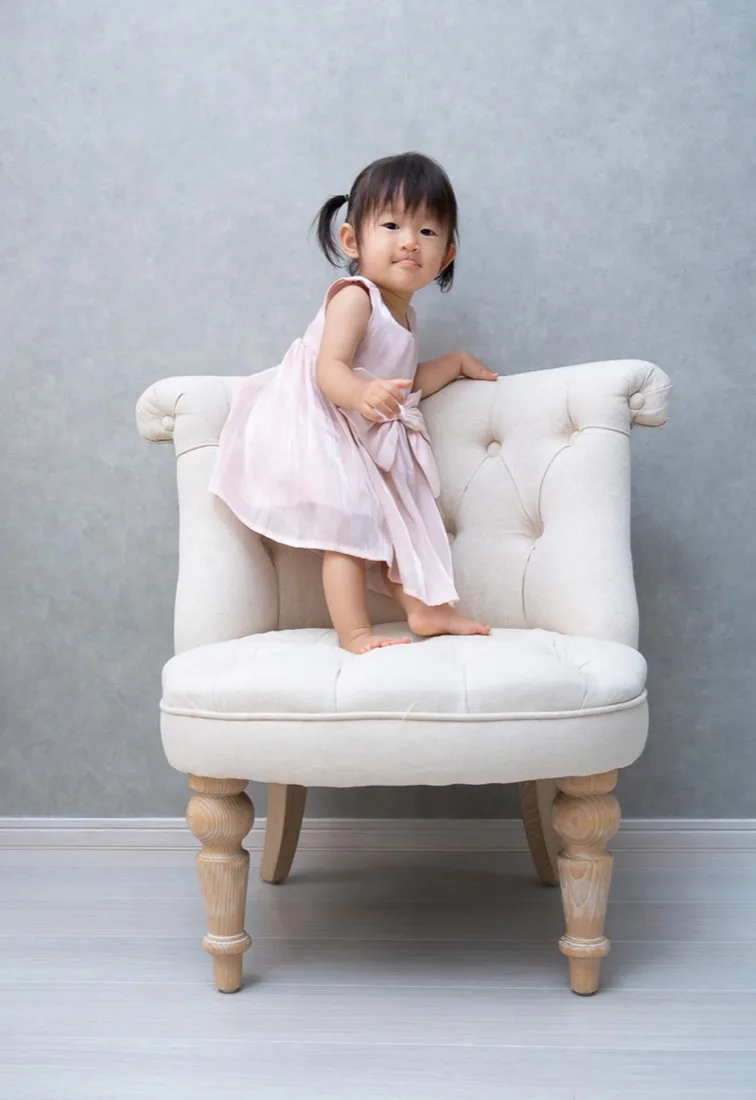 白い椅子の上に立つ1歳の子ども